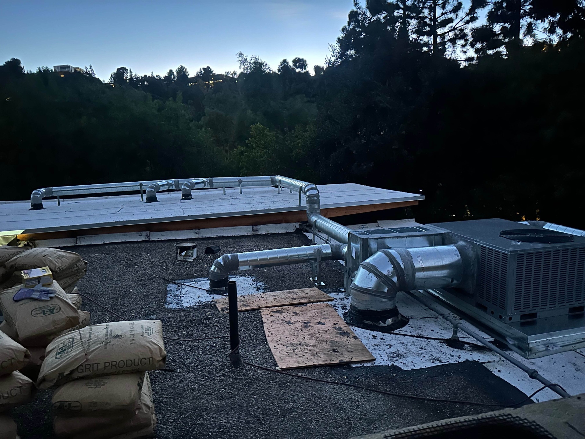 Galvanized HVAC ductwork and package unit on a flat commercial roof